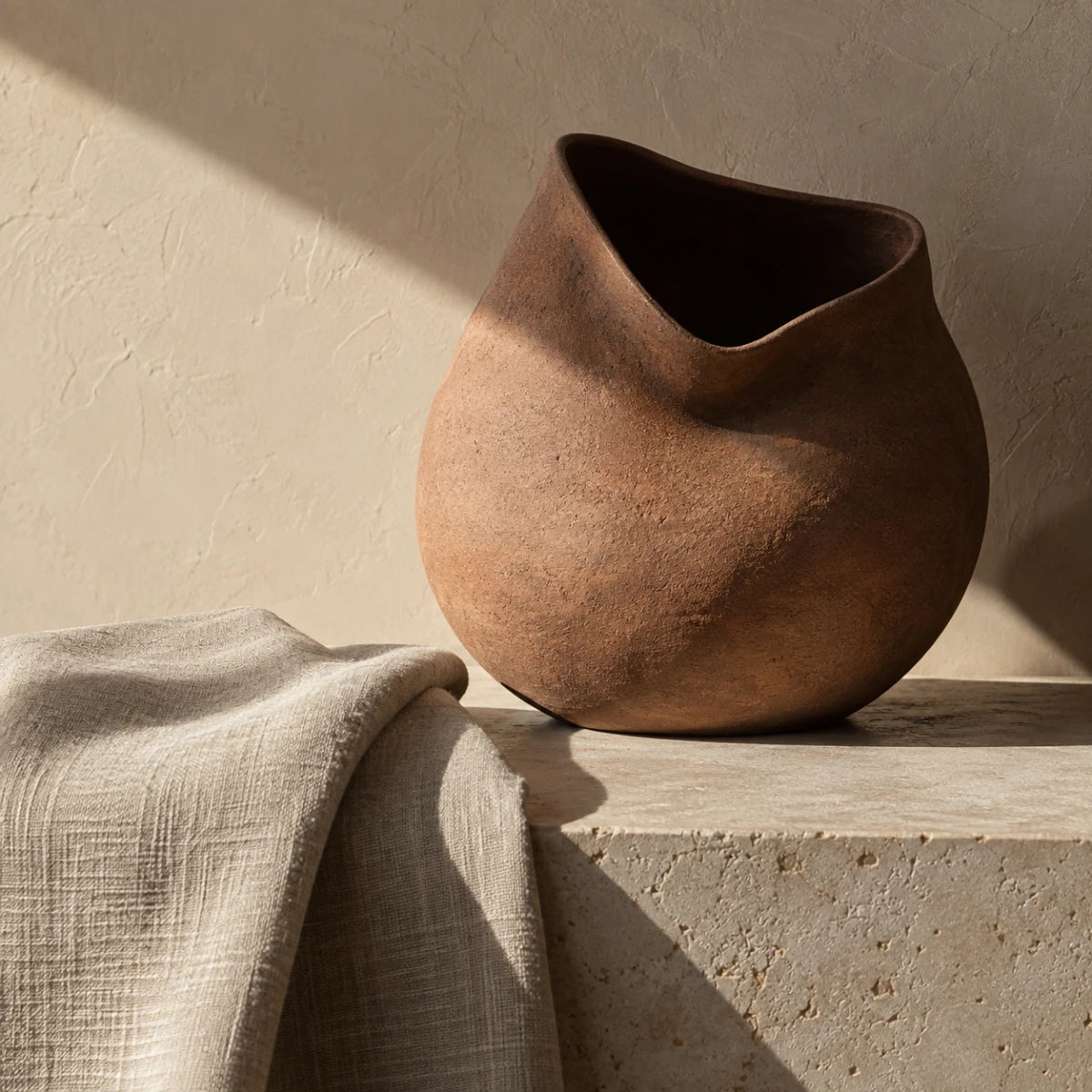 Asymmetric clay vessel and linen in warm directional light